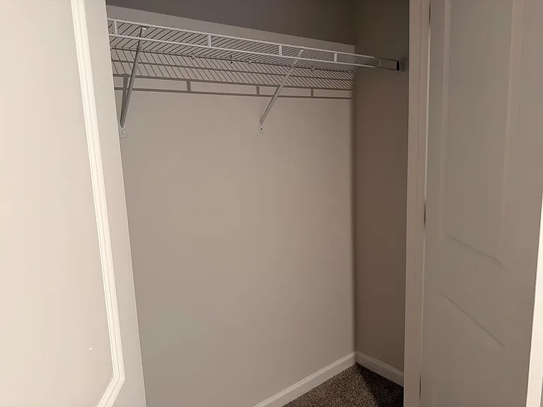 Dedicated closet space with a sturdy wire shelf and hanging rod, offering convenient storage for clothes and essentials.