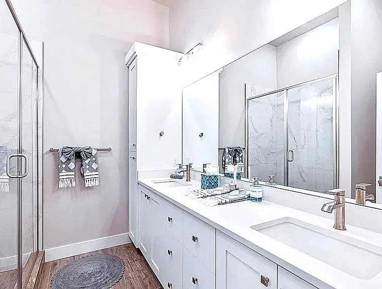 Elegant bathroom with double vanity, marble-look tile, glass-enclosed shower, and modern fixtures