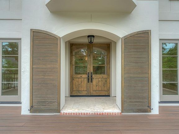 The gorgeous stucco elevation showcases beautiful details including wood shutters that frame the rich stained front doors.