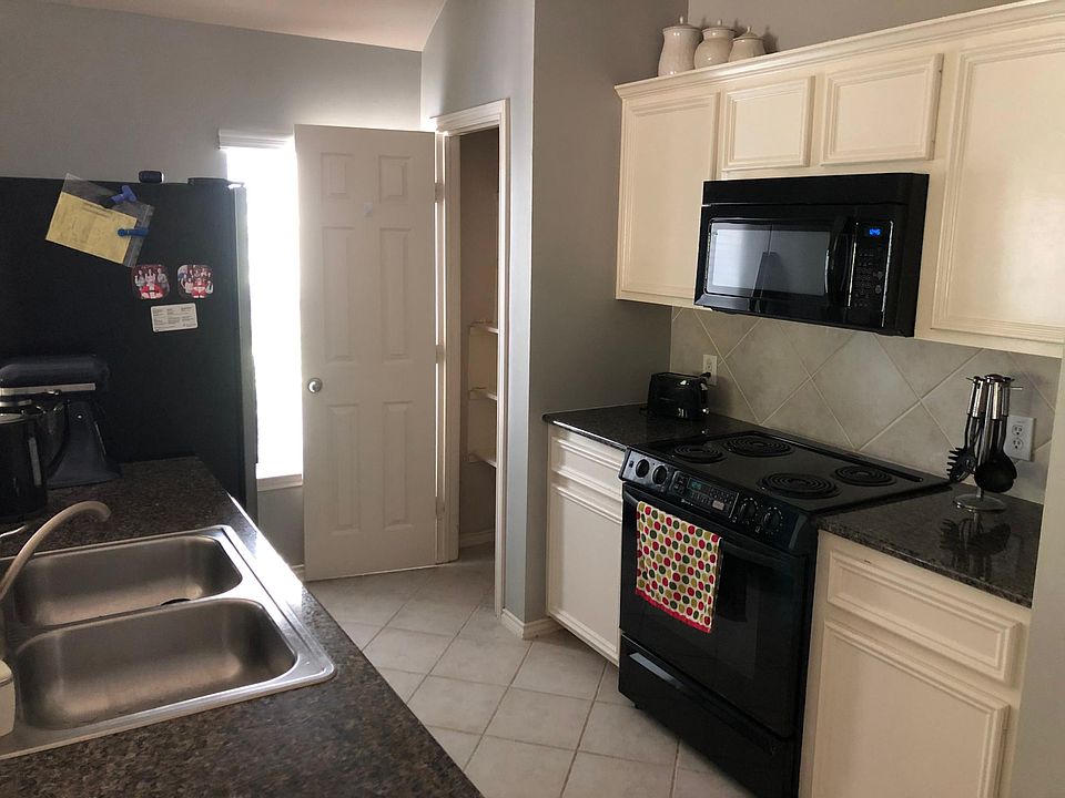 Updated kitchen with modern black appliances and stainless steel sink.