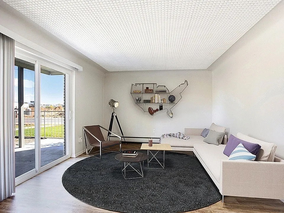 Bright and modern living room with a cozy L-shaped sofa, contemporary decor, and large sliding glass doors leading to a balcony with a view.