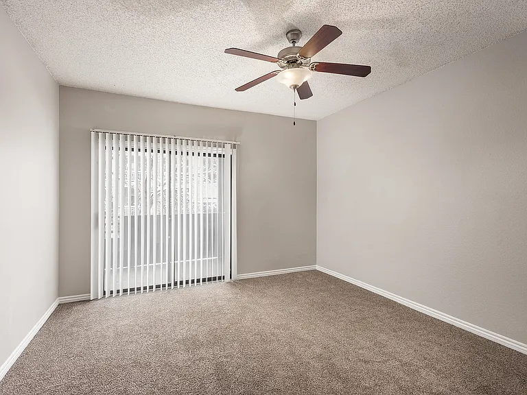 I64A0508Bright and airy room with plush carpet, modern ceiling fan, and sliding glass doors leading to a private balcony, perfect for relaxation and comfort.Edit