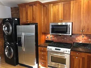 Kitchenaid Stainless Steel Refrigerator with ice and filtered water dispenser in door; full size kitchen aid microwave with turntable and full size gourmet kitchenaid gas range; kitchen designed with granite and matching exposed brick design backsplash.