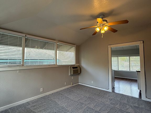 Spacious living room with many windows, doorway takes you to the kitchen