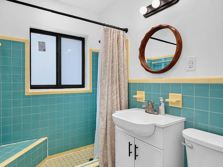 Full bathroom with tiled tub/shower, vanity storage, and a window for ventilation and natural light.