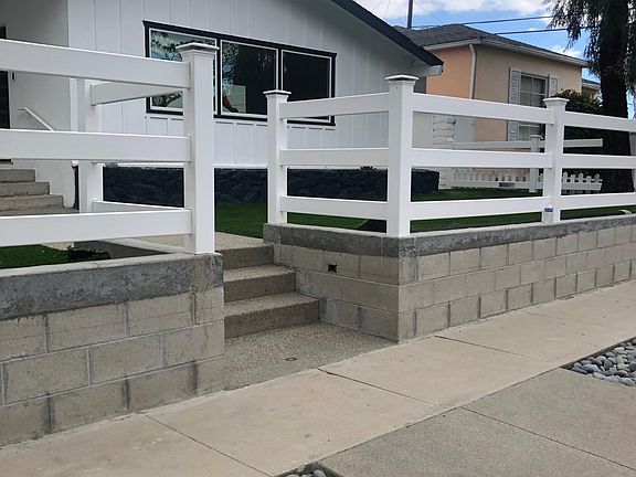 Front of house on sidewalk, white stucco going on wall.