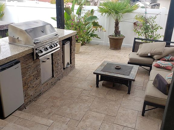 covered back patio with built-in grill and fan and mini refrigerator.