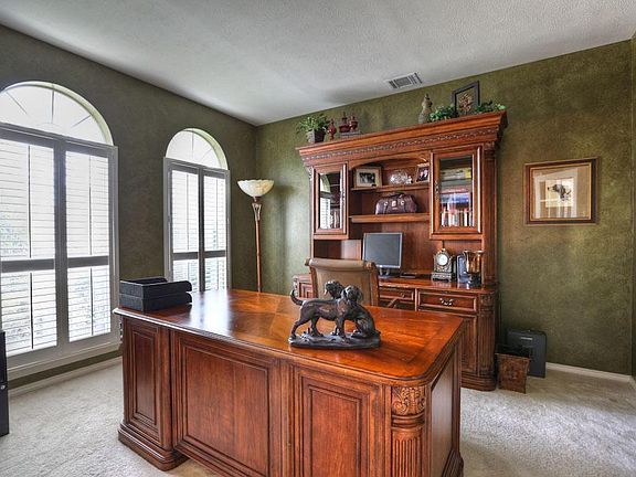 Through double French doors is the STUDY 13x11, highlighted with faux painted walls, Plantation shutters covering tall arch topped windows, and neutral carpet. The room could function as a Formal Living Room or Music Room, if needed.