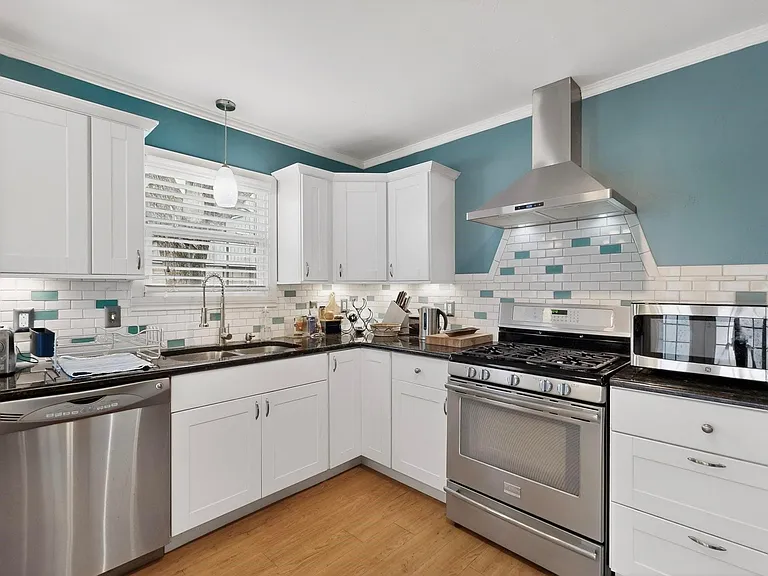 A modern kitchen showcasing white cabinetry and stainless steel appliances, blending style and functionality.
