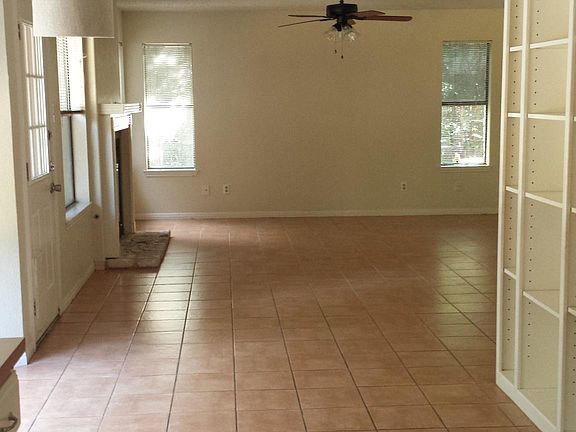 downstairs view from edge of kitchen/eat in dining area looking towards back living room with built in shelves and wall of windows
