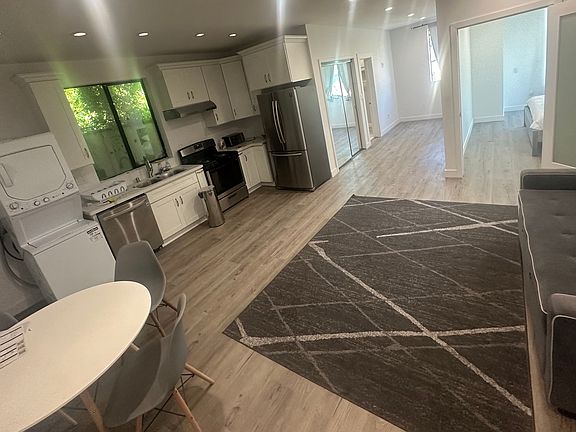 Kitchen area and living room area with full appliances.

The space includes a stack-up laundry machine (washer and dryer) on the left for maximum convenience