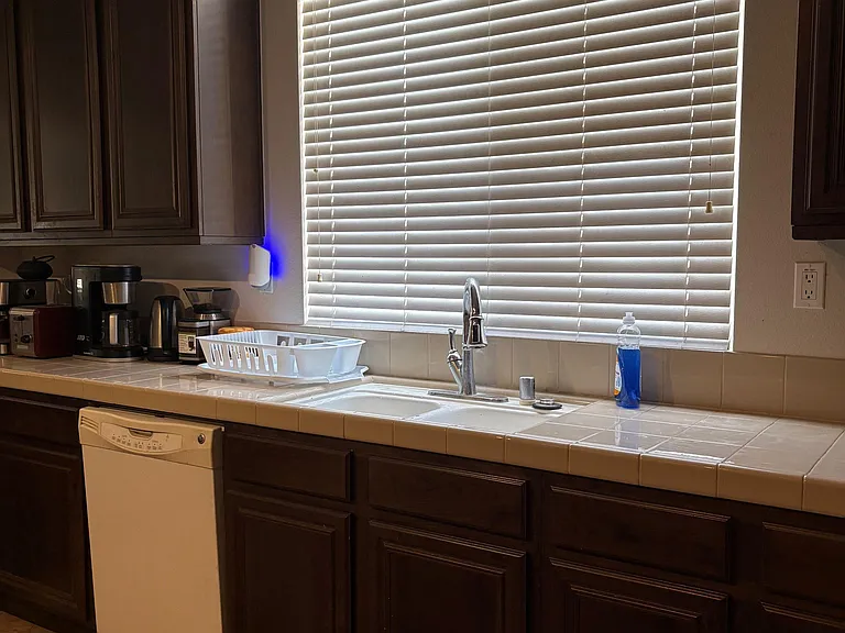 Kitchen workspace featuring generous tile countertops, ample cabinet storage, and a window over the sink for natural light.