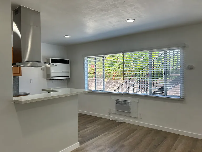 Kitchen on left, dining area on right of kitchen, natural light from window.