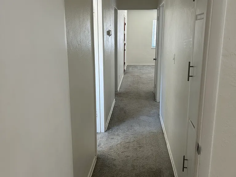 Standing at the Primary bedroom, looking down the hallway towards the living room and front door.
