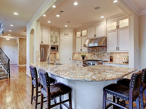 This immaculate kitchen is a chefâs dream! Granite counters, decorative stone backsplash, six-burner stove, double oven, lighted display cabinets, and tons of storage are just a few of the upgrades in this high-end kitchen.