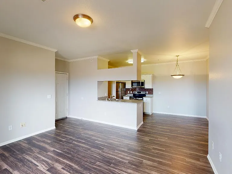 Apartment kitchen, dining and living room with wood-style flooring in select homes.