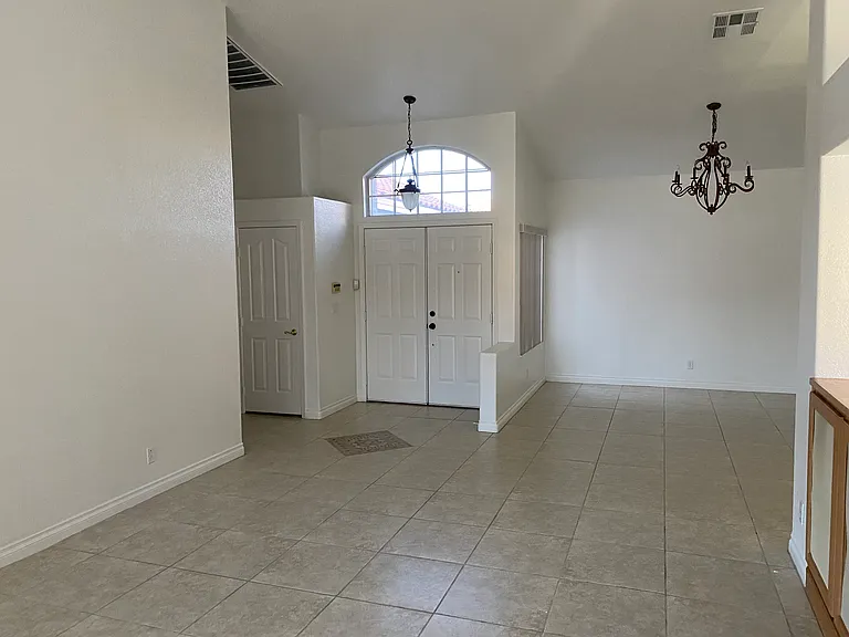 View of the front double-doors from the living room. Formal dining area. Home alarm by the door.