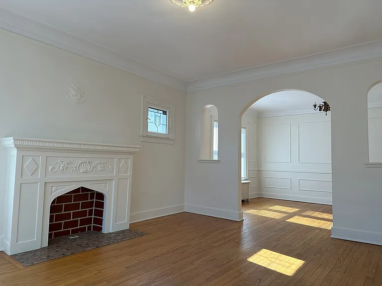 Living room with a "for decoration only" fireplace. Leaded glass decorative window. Beautiful hardwood floors.