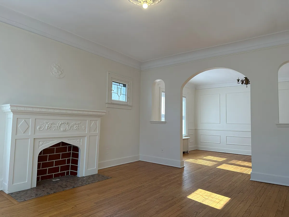 Living room with a "for decoration only" fireplace. Leaded glass decorative window. Beautiful hardwood floors. - 1001 Beaconsfield Ave