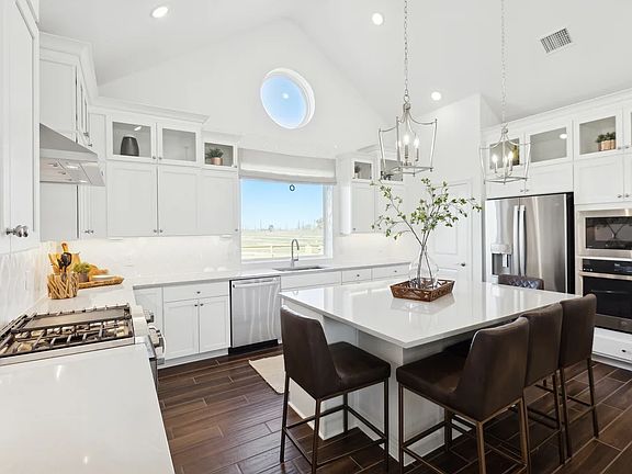 Kitchen with glass upper cabinets and vaulted ceiling