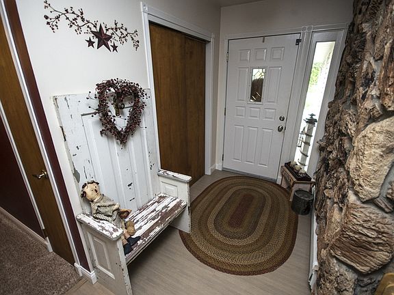 Walk in to the entry of this fabulous home with new high end wood laminate flooring. View of the back side of the unique, large stone fireplace in the living room accents the left wall.  Coat closet located to the right. 