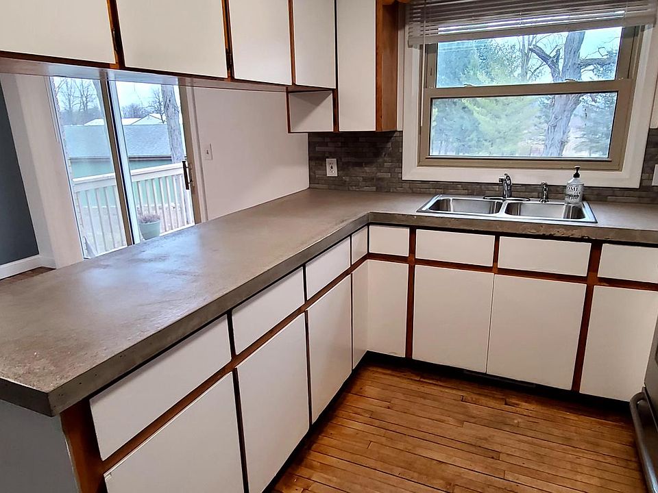 Kitchen with custom concrete counter tops and stainless steel sink and appliances.