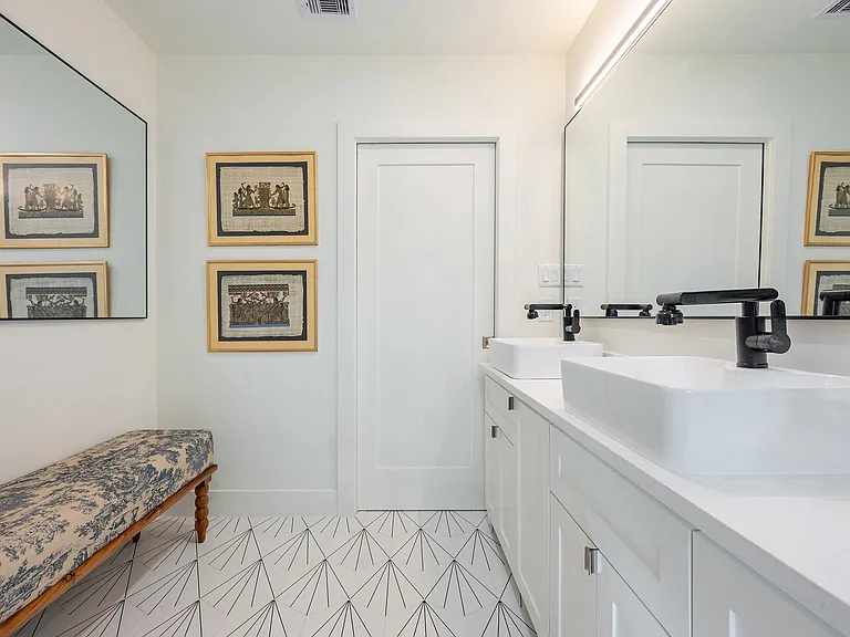 Bright bathroom with double vanity, sleek lighting, seating area, and clean contemporary finishes.