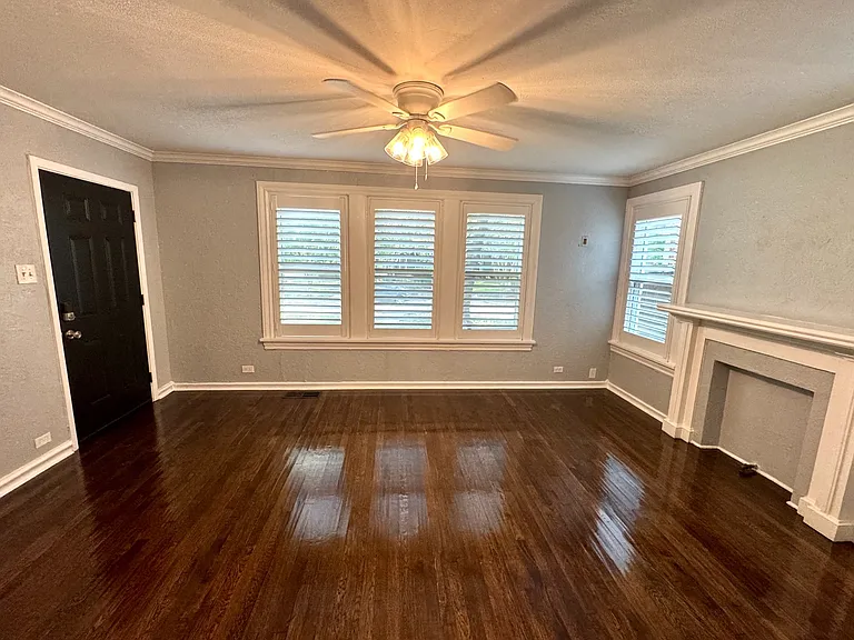Living room, gorgeous hand scraped hardwood floors, front door of duplex, custom wood plantation shutters, and feaux fireplace.