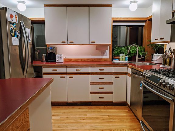 Cute, sunny kitchen with gas range and stainless steel fridge.