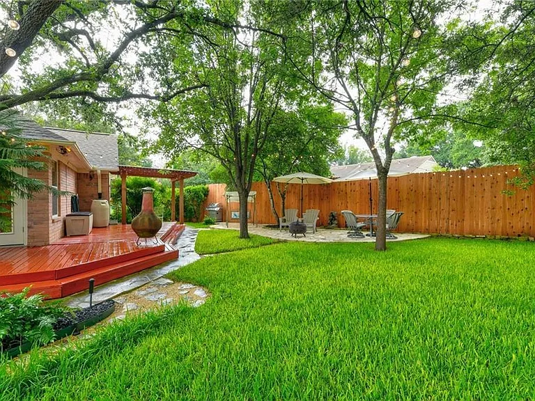 Beautifully landscaped backyard with deck and water feature.