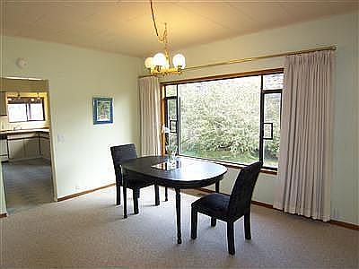 Dining room with kitchen in background. Window looks out on the side yard.
