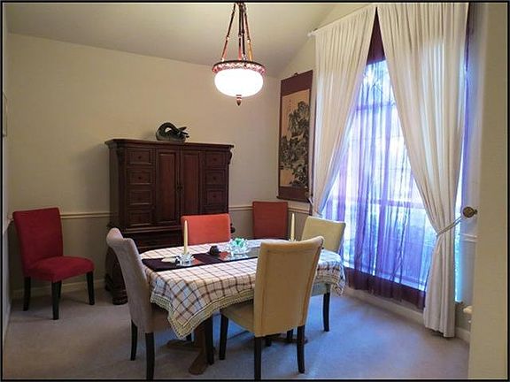 FORMAL DINING ROOM WITH VAULTED CEILINGS AND LARGE WINDOW FOR NATURAL LIGHT.