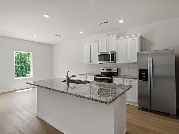 The kitchen has stainless steel appliances and plank flooring.