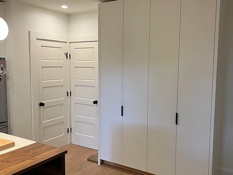 Custom built pantry keeps everything in order. The two doors are to the powder room and the basement.
