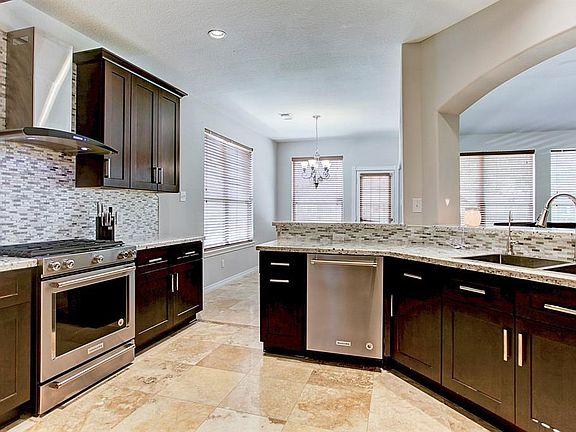 The kitchen displays Travertine floors with marble insets, SS appliances and an incredible tile backsplash.  This color scheme is very neutral.  The SS gas range and a overhead vent system is beautiful and brings so much functionality to the kitchen.  All appliances are KitchenAid.