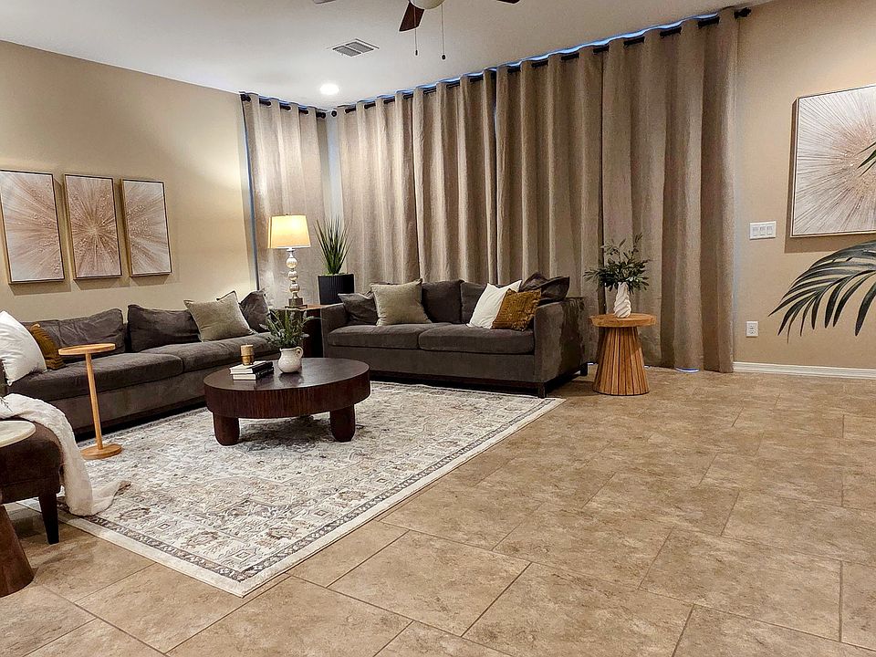 Spacious, modern great room featuring a tall, neutral toned wall adorned with a triptych of abstract art.