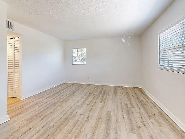 Bright, spacious room with elegant light wood flooring and large windows offering abundant natural light, ideal for versatile living or bedroom space.