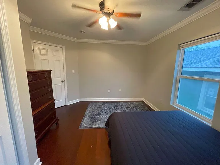 Bedroom 1 furnished with a queen bed, dresser, and closet, plus a large window for natural light.