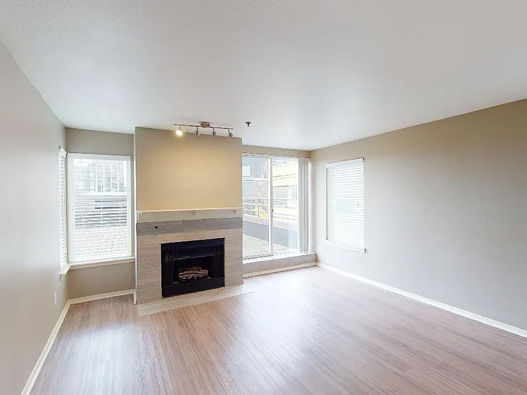 Apartment living room with wood-style flooring and fireplace in select homes.
