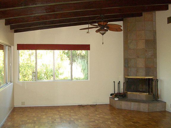 Living Room with Beamed Ceiling, Wood Burning Fireplace, & Parquet Flooring