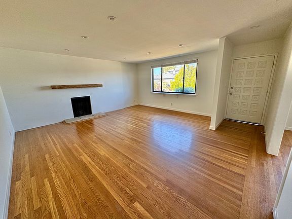 Large living room with gas fireplace and mantel, connects to the dining room