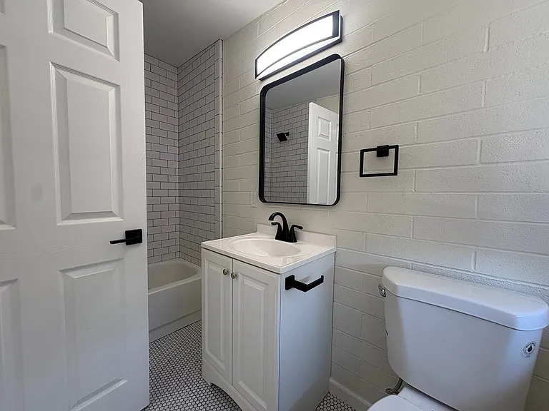 Bathroom with shower / tub combo, new penny tile and subway tile, toilet and vanity.