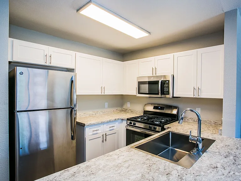 Fully equipped kitchen with stainless steel appliances, white shaker cabinets, and granite counters.