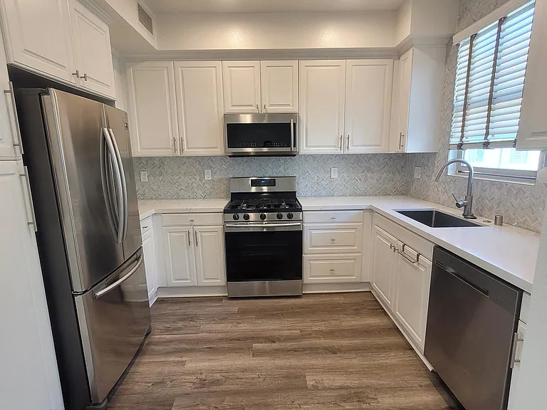 Designer remodeled kitchen, with white and gray quartz countertops, and luxury Carrera marble backsplash to the ceiling.