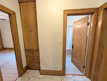 View from Kitchen into living space hallway. Linen closet to the left of bathroom which is straight ahead. Main bedroom to the left. Second bedroom to the right.