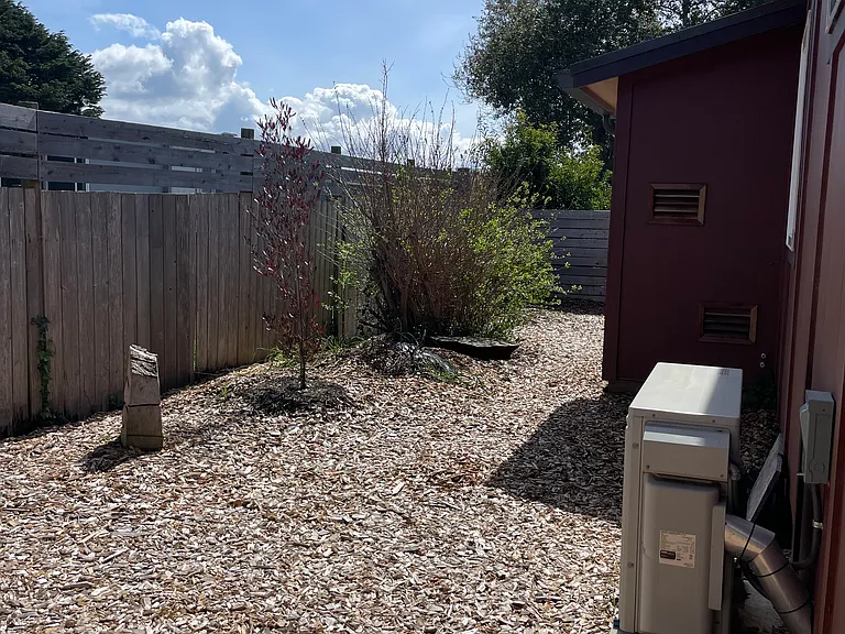 Behind the house with the heat pump.