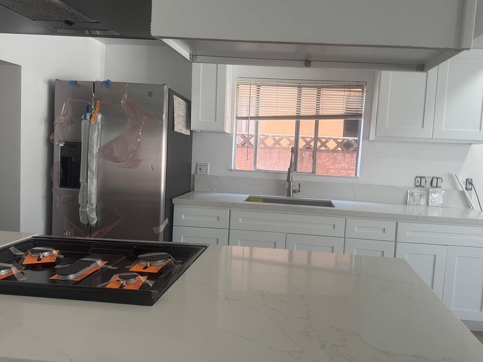 Kitchen island. New appliances. Blinds, outlet, and switches are being installed.