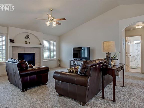 Living room with ceiling fan, lots of space and cozy fireplace.