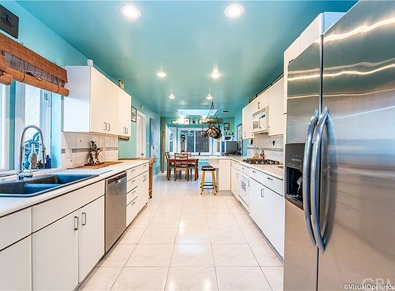 Kitchen with white cabinets and stainless steel refrigerator and dishwasher.