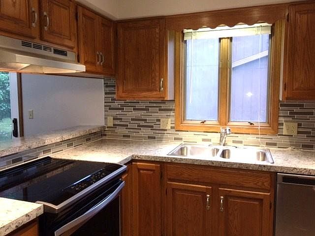 Kitchen w/ tile backsplash and new stainless steel appliance